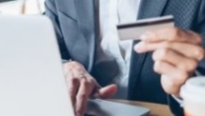 A man holds a credit card as he inputs information into a laptop.