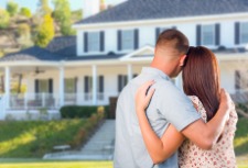 A man and a women hug while looking at their dream home.