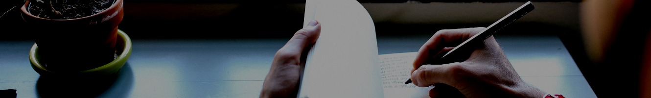 A man writes in a journal on his desk.