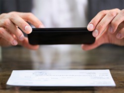 A man uses his cellphone to take a photo of a check and deposit it into his bank account.