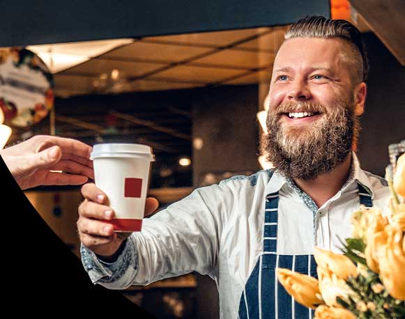 A man hands over a coffee to a customer. 