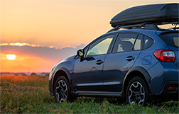 A car parked on a hill during sunset. 