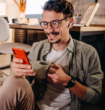 Man looking at phone with coffee at home.