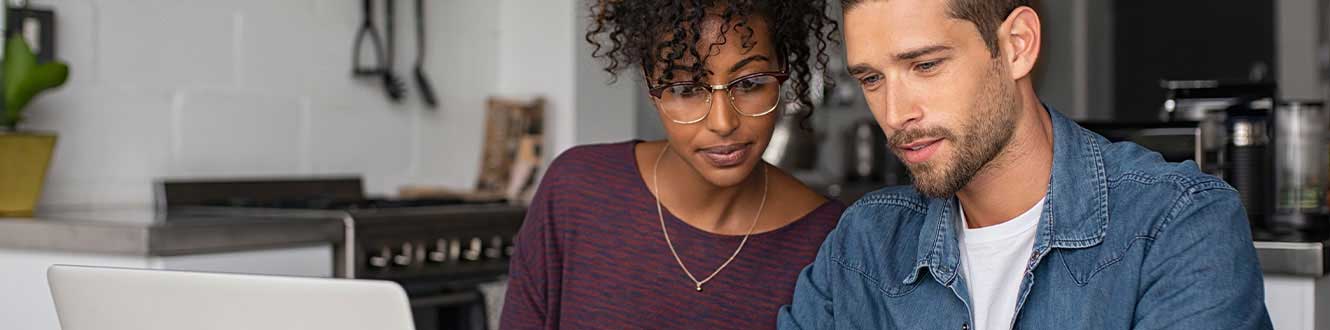 A man and a woman look at a laptop.