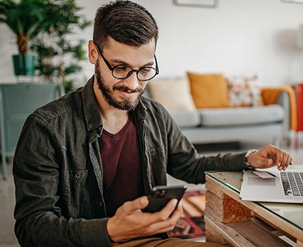 Man using phone and laptop at home.