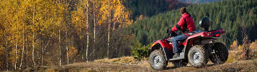 A man sitting on a four wheeler on top of a mountain.