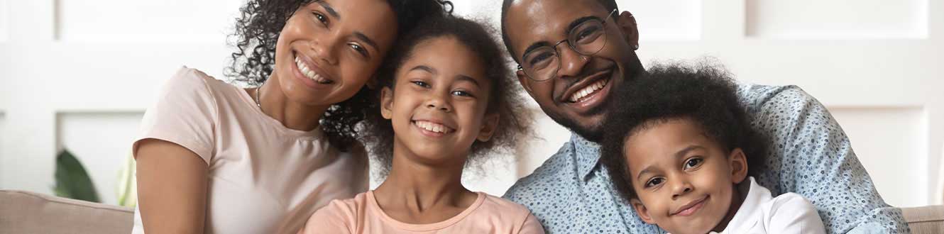 A family sitting on a couch smiling.