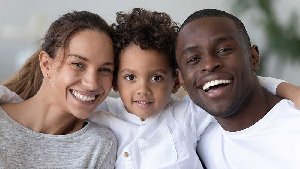 A man, woman, and small child look at the camera and smile.