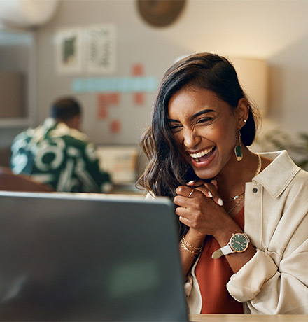 Woman excited sitting behind her laptop.