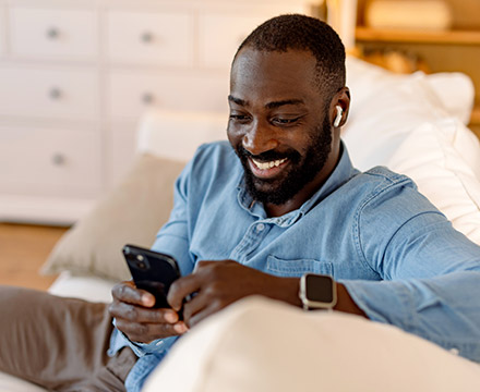 Man using phone on couch at home.