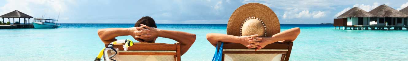 A man and a woman relax on beach chairs.