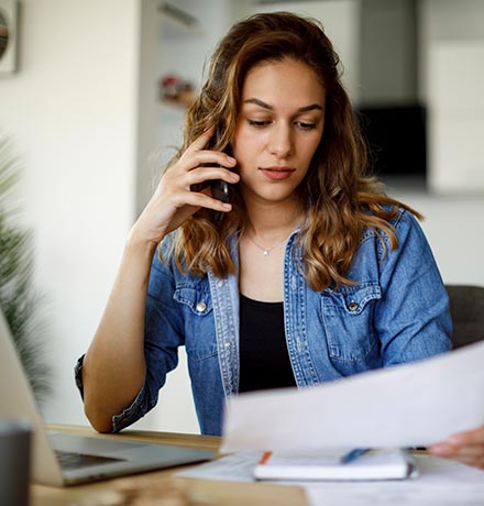 Woman on the phone looking at papers at home.