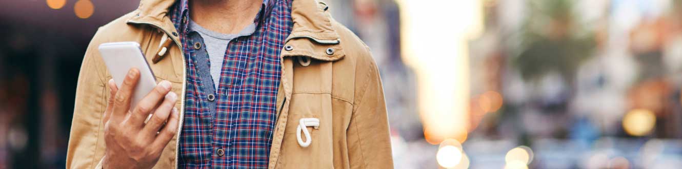 A man using his mobile phone while walking on a city street.