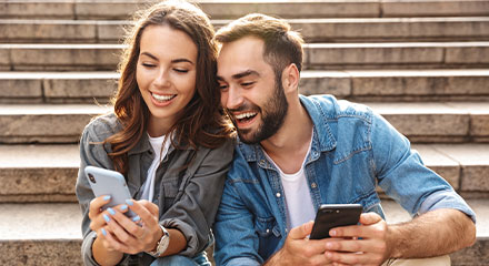 Couple on phones sitting on stairs.