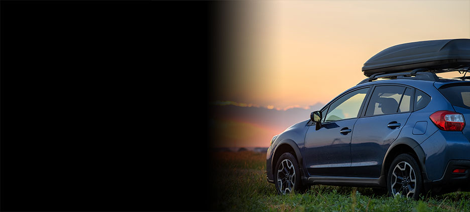 A car parked on the grass during sunset. 