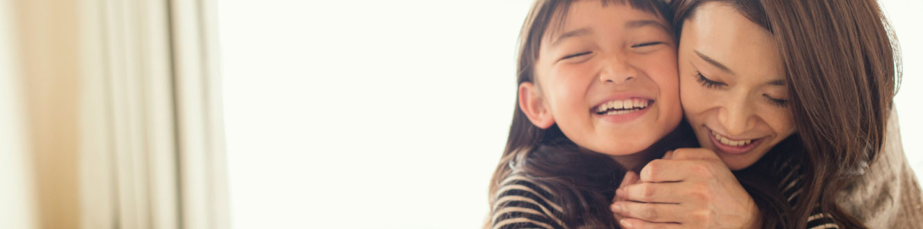 A woman hugs her daughter and smiles.